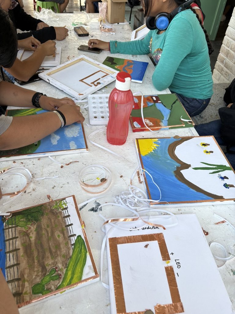 El grupo trabajando junto en los lienzos pintados, varias manos sobre la misma pieza