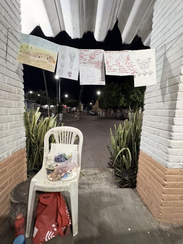 De noche, en un zagu&aacute;n de ladrillo blanco, los dibujos del taller colgados de un cordel; abajo, una silla de pl&aacute;stico con pinceles, una paleta y una botella de agua