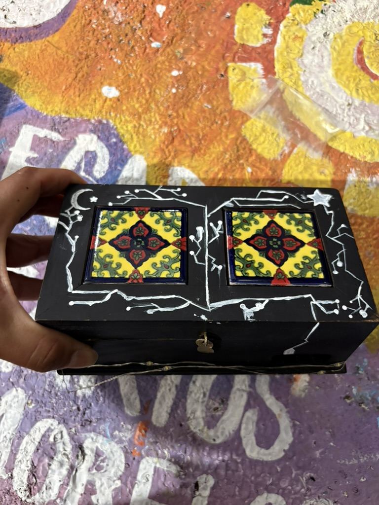 Una caja de madera negra con dos azulejos de talavera en la tapa