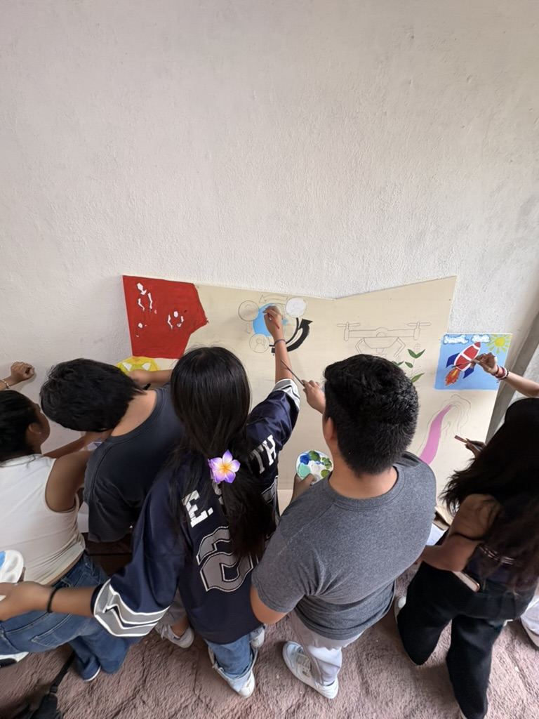 Varias personas pintando al mismo tiempo sobre el tablero, con pinceles y paletas