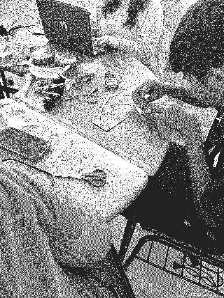 Unas manos conectando una placa peque&ntilde;a sobre la mesa, con cables, un porta pilas y unas tijeras alrededor