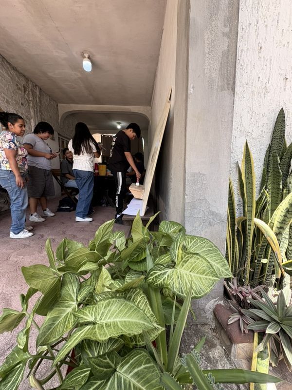 El pasillo del taller visto desde las plantas: el tablero recargado en la pared y varias personas pintando y conversando